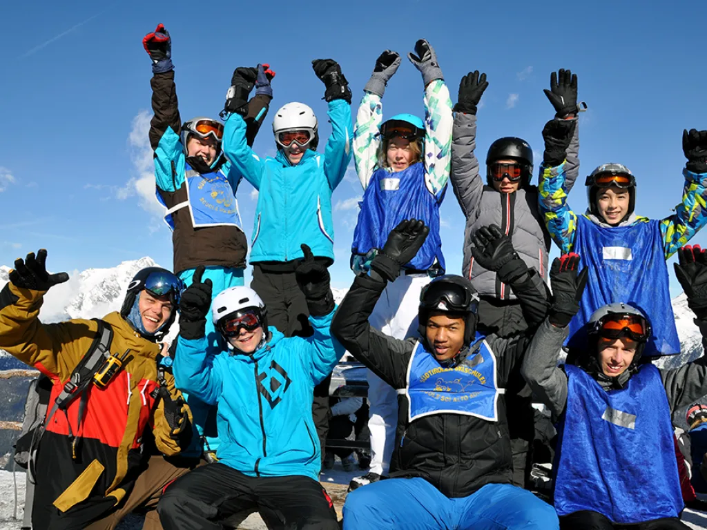 Gruppe jubelt im Schnee mit erhobenen Armen.